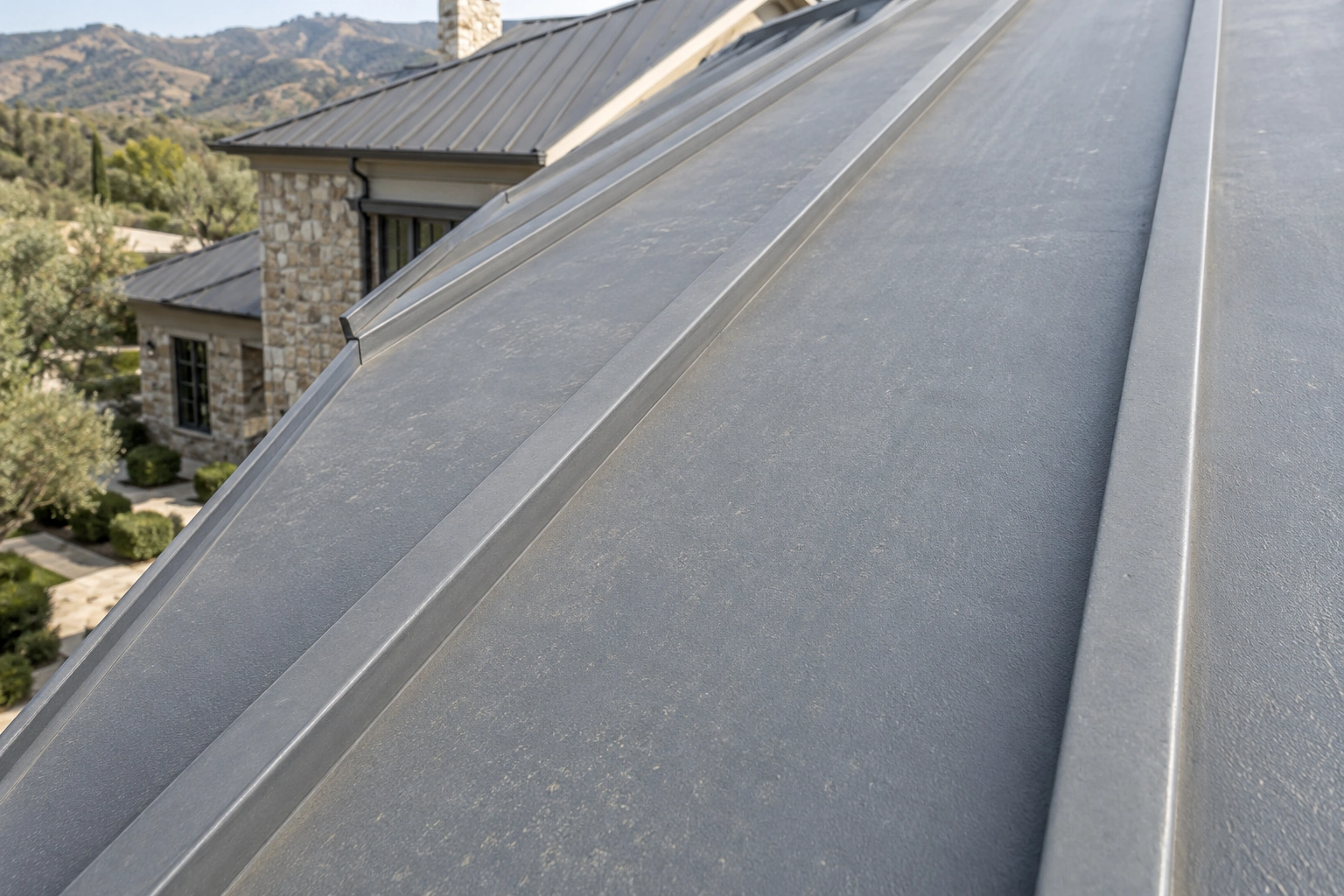 Close view of raised standing seams and coated gray metal roof panels